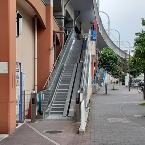 An outdoor escalator to an above-ground train platform.