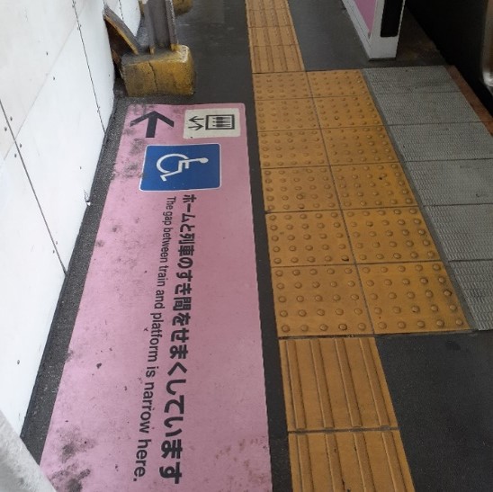 A designated section of a subway platform with accessible features including yellow tactile attention indicators.