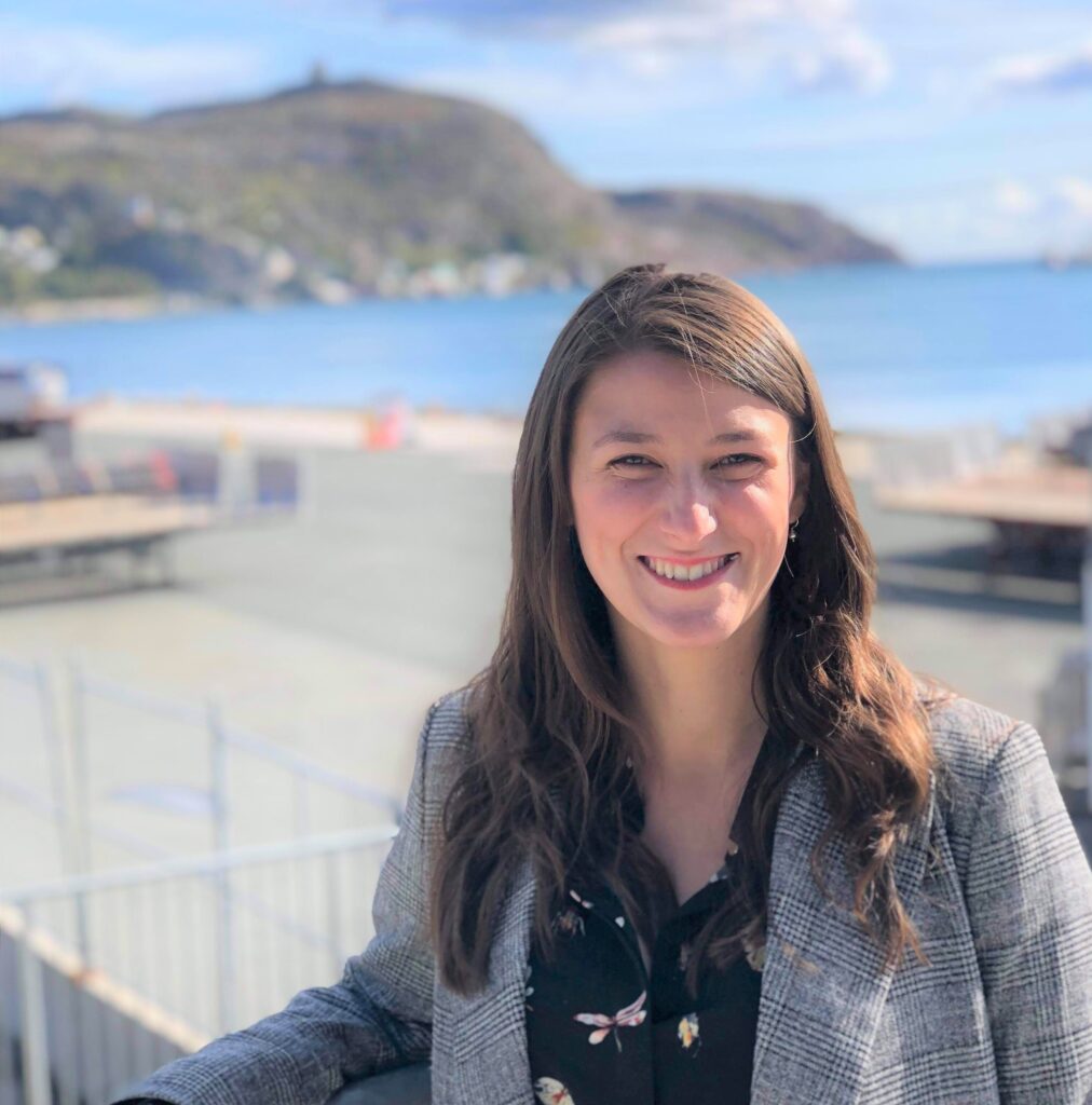 A smiling woman posing in front of a natural landscape