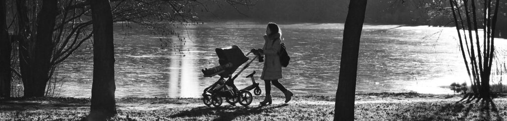 A woman pushes an enfant in a baby carriage along a pedestrian path