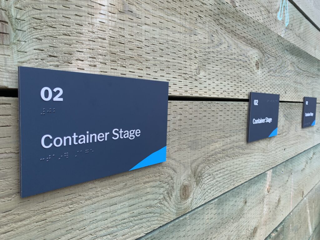 Three blue signs mounted to a wooden wall.