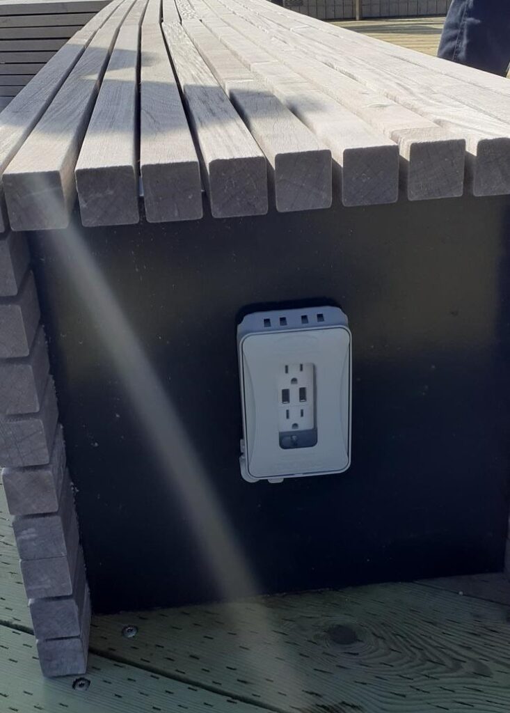 A white electrical outlet on outdoor seating on the viewing deck.